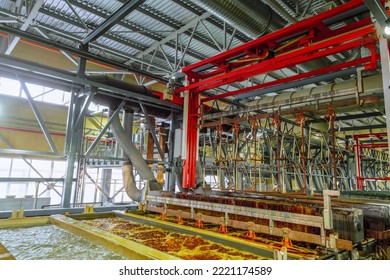 Production process of galvanic copper, nickel and chrome plating steel metal products. Lifting of metal products by overhead crane from bath of electrochemical plating. Fragment of a galvanic line. - Shutterstock ID 2221174589