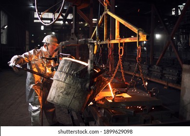 Production of steel castings in an industrial smelter company. Foundry worker filling molds with liquid steel.