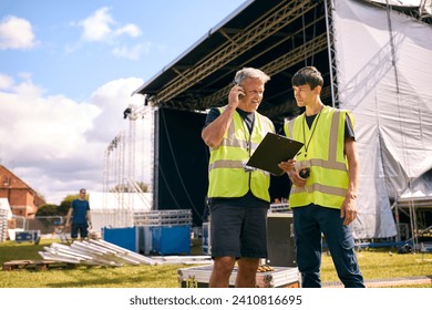 Production Team Talking On Radios And Setting Up Outdoor Stage For Music Concert Or Festival