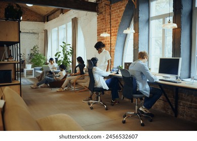 Productive coworking. Young people in modern office, maintaining productivity, working on gadgets. Positive ad comfortable atmosphere. Concept of business and education, co-working space - Powered by Shutterstock