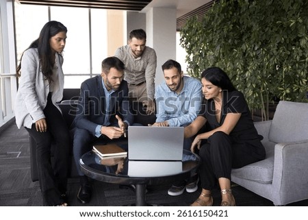 Productive workflow using modern tech of five diverse employees gather in office lobby area, look at device screen, analyze data, reviewing report, going over key metrics or visual aids. AI, business