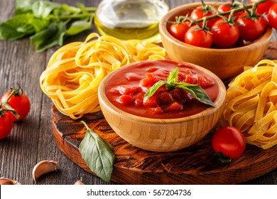 Products For Cooking - Tomato Sauce, Pasta, Tomatoes, Garlic, Olive Oil On The Old Wooden Background.