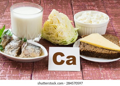 Products - a source of calcium (sardines in oil, cabbage, milk, cottage cheese, brown bread, cheese) on wooden burgundy background
