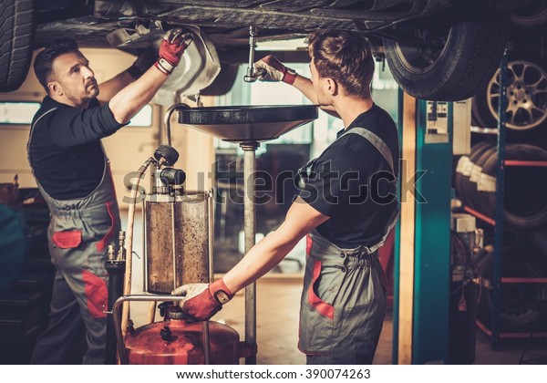 Profecional car  mechanic changing motor oil in\
automobile engine at maintenance repair service station in a car\
workshop.