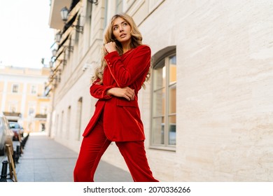 Profeshional fashion model in  elegant red velvet suit posin outdoor in old european city. 