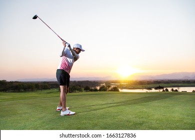 Professinal Golf Player On Golf Course. Pro Golfer Taking A Shot At The Sunset