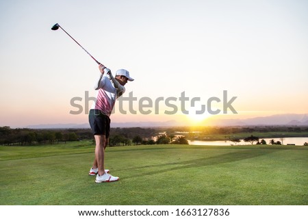 Professinal golf player on golf course. Pro golfer taking a shot at the sunset
