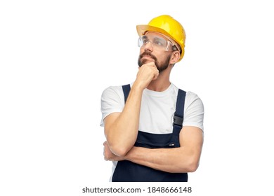 profession, construction and building - thinking male worker or builder in yellow helmet and goggles over white background - Powered by Shutterstock