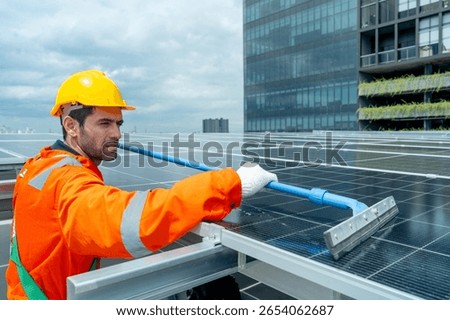 Profession engineer or technician worker use cleaning brush to clean solarcell panel in area of rooftop of building.