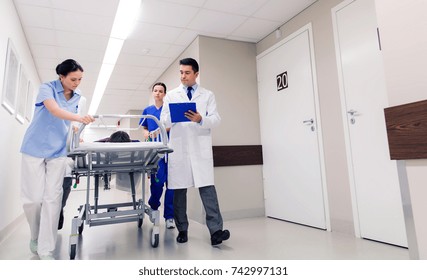 profession, people, health care, reanimation and medicine concept - group of medics or doctors carrying unconscious woman patient on hospital gurney to emergency - Shutterstock ID 742997131