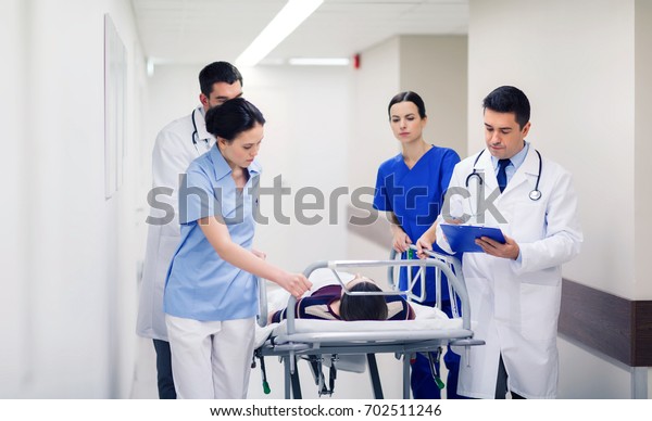 profession, people, health care,\
reanimation and medicine concept - group of medics or doctors\
carrying unconscious woman patient on hospital gurney to\
emergency