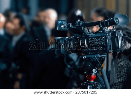 Professional 4k digital video camera and accessories in a conference. Blury people in the background. 