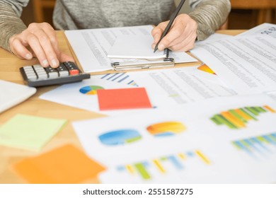 Professional Accountant Analyzing Financial Reports Using Calculator And Business Charts To Illustrate Stock Market Growth And Marketing Strategies For Success In Office Or Home Workspace Settings. - Powered by Shutterstock