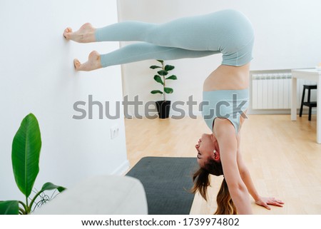 Professional acrobat in the lockdown does stretching at home. Beautiful young girl in a sports suit does exercises