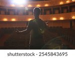 Professional actor rehearsing on stage in theatre, back view