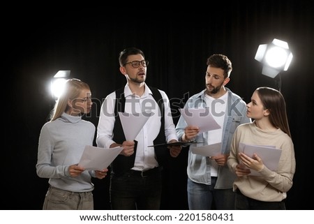 Professional actors reading their scripts during rehearsal in theatre