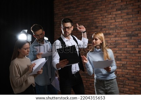 Professional actors reading their scripts during rehearsal in theatre