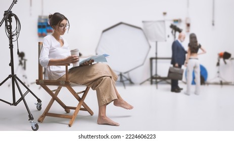 Professional Actress Sitting On The Director's Chair And Reading The Script, Film Studio Interior In The Background: Film Industry And Video Production Concept