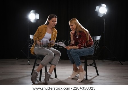 Professional actresses reading their scripts during rehearsal in theatre