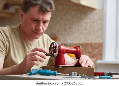 Professional adjustment of a sewing machine. Focus on the sewing machine. Male master repairs the sewing machine. Inspection of the mechanism in search of a breakdown - Powered by Shutterstock