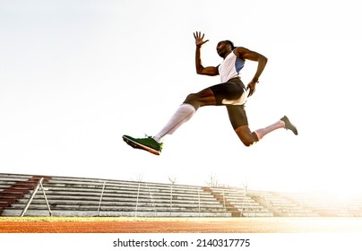 Professional african american male track and field athlete during obstacle race - Young athlete performing explosive long jump during training on race track in athletics stadium - Freedom concept - Powered by Shutterstock