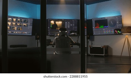 Professional African American video editor makes color grading in program on PC. Process of colour correction for movie post production in modern studio. Multiple monitors with action film footage. - Shutterstock ID 2288811955