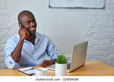 Professional African Black Man Talking On Mobile Cell Phone To Clients In Office With Laptop Computer