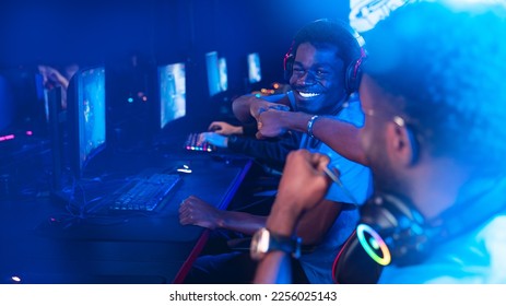 Professional african cyber gamer greeting and support team fists hands online game in neon color blur background. - Shutterstock ID 2256025143