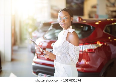 Professional african female salesperson working in car dealership