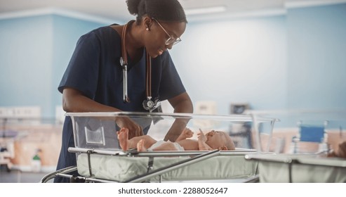 Professional African Nurse Soothing an Adorable Small Caucasian Newborn Child in Nursery Clinic. Medical Health Care, Maternity Hospital and Parenthood Concept - Powered by Shutterstock