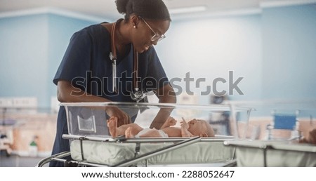 Professional African Nurse Soothing an Adorable Small Caucasian Newborn Child in Nursery Clinic. Medical Health Care, Maternity Hospital and Parenthood Concept