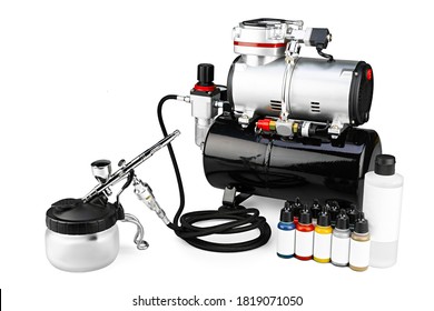 professional airbrush compressor starter set equipment with chrome metal gun acrylic paint and thinner bottles isolated on white background. Industry hobby and art concept.