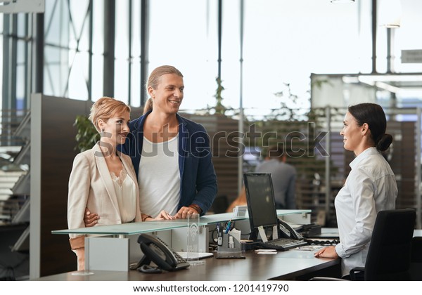 Professional ambitious sales agent prompting\
the young couple to buy a luxury car in the car dealership, telling\
about features and advantages of new\
vehicle