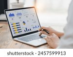 Professional analyzing financial data graphs, charts on laptop display at a modern workspace. Financial analysis or business evaluation concept