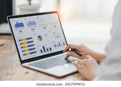 Professional analyzing financial data graphs, charts on laptop display at a modern workspace. Financial analysis or business evaluation concept