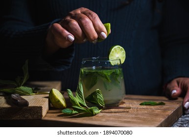 Professional Anonymous Barman Squeezing Lime With Hand While Making Mojito Cocktail. Worker Woman Preparing Cocktails At Home