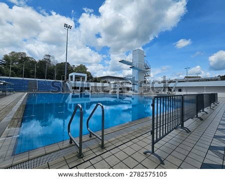 Professional aquatic facility featuring diving platforms, spectator seating, and competition‑grade swimming pool under clear skies.