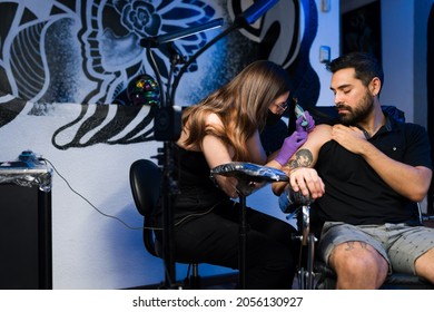 Professional artist and male customer at the tattoo shop. Hispanic young man getting a new tattoo on the arm - Powered by Shutterstock