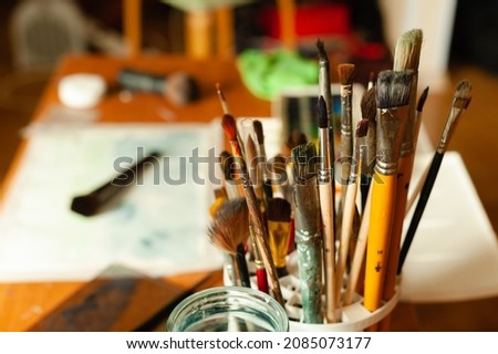 Professional artist's brushes with paint residues in an art workshop.