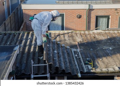 Professional asbestos removal. Men in protective suits are removing asbestos cement corrugated roofing