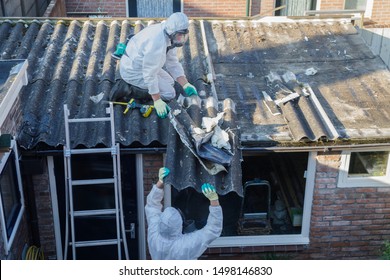 Professional asbestos removal. Men in protective suits are removing asbestos cement corrugated roofing