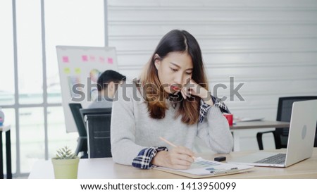 Professional Asian businesswoman working at her office via laptop. Young Asian female manager using portable computer device while sitting at modern workplace.