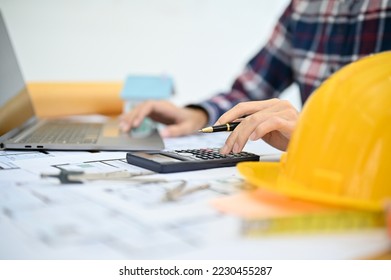 Professional Asian female architect or engineer using scientific calculator and laptop computer, working in her office. cropped shot - Shutterstock ID 2230455287