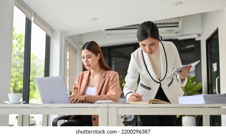 A Professional Asian Female Business Analyst Team Working Together, Concentrating On Their Assignment, Using Laptop Computer And Checking The Report.