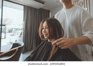 Professional asian hairdresser man checking hair of young beautiful asian woman in beauty salon. - Powered by Shutterstock