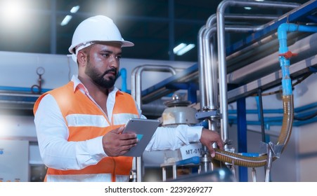 Professional Asian male engineer in helmet using the tablet to work, inspect and maintain electrical cabinet. Machines in a beverage factory, beverage industry concepts expert worker - Powered by Shutterstock