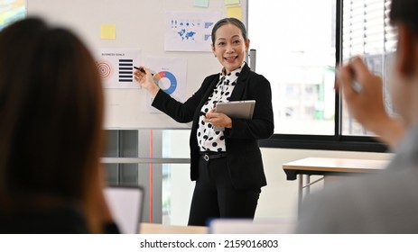 Professional Asian Senior Female Boss Leading A Corporate Team Meeting, Mentoring, Coaching And Presenting Project Goals To Young Team.