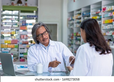 Professional Asian Senior Male Pharmacist Prepare Prescription Medicine Capsule Or Supplementary Food To Female Patient In Hospital Pharmacy Drugstore. Medical, Pharmaceutical And Healthcare Concept.