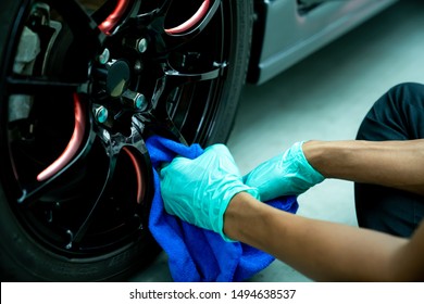 A professional Asian  technician cleaning the wheel car with the fabric wearing  plastic gloves on hands. Cleaning and whipping car wheel alloy. - Powered by Shutterstock