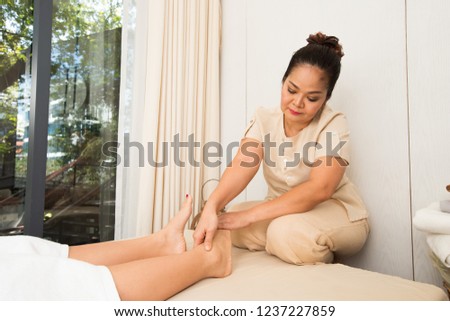 Professional Asian Therapist twist and massage spa on foot of customer to release stress relax muscle pain or injury. Physiotherapist pressing hard fingers thumb on specific spots of female palm feets